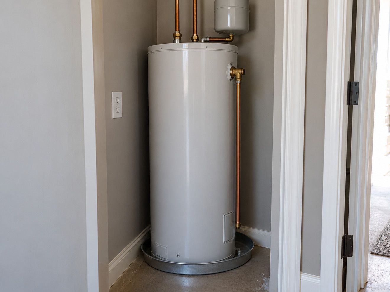 Tank water heater in a utility closet with an expansion tank, relief valve pipe and drain pan